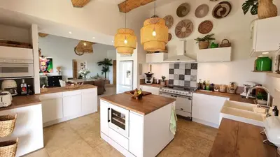 a kitchen with white cabinets and wooden counter tops at La Balinaise in Apt