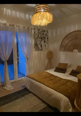 a bedroom with a bed and a chandelier at La Balinaise in Apt