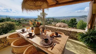 a wooden table with chairs and a view of the mountains at La Balinaise in Apt