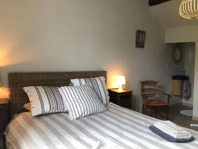 a bedroom with a bed with striped pillows and a chair at Le 140 du Ventoux in Saint-Saturnin-lès-Avignon