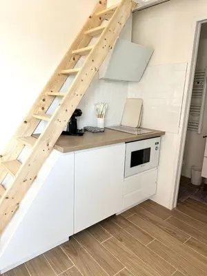 a kitchen with white cabinets and a staircase at La maisonnette de Tom in Caumont-sur-Durance