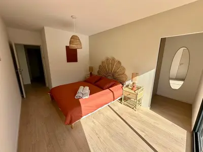 a bedroom with a bed with orange sheets and a mirror at Villa Provençale in Le Thor