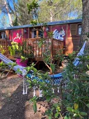 a red caravan with a deck and a tree at Appel du Luberon in Mérindol