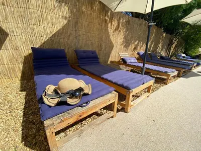 a group of lounging chairs with hats and an umbrella at Le Mas des iscles Mallemort in Mallemort