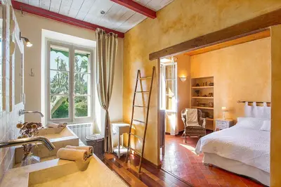 a bedroom with a bed and a bathroom with a sink at Mas des Olivades - Ferme Provençale - Piscine in Pernes-les-Fontaines