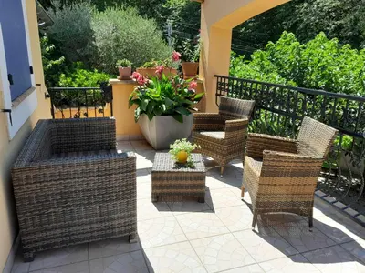 a patio with wicker chairs and a table with flowers at Résidence Les Salettes in Mormoiron