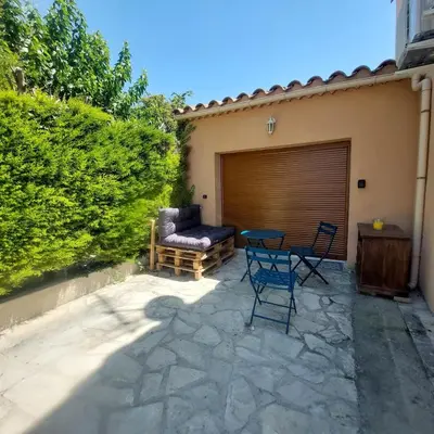 a patio with a table and chairs next to a garage at Studio 25m2 in LʼIsle-sur-la-Sorgue