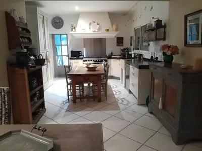 a kitchen with a table and a kitchen with white appliances at La Bartavelle in Eyragues