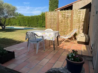 a patio with a table and chairs and a fence at Studio en Provence avec piscine in La Barben