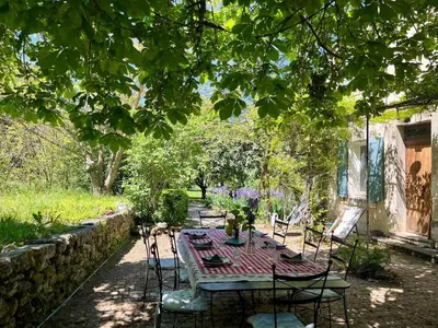 a table and chairs in a garden under a tree at Très beau mas à Bonnieux in Bonnieux