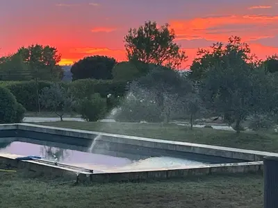 a swimming pool with a sunset in the background at Très beau mas à Bonnieux in Bonnieux