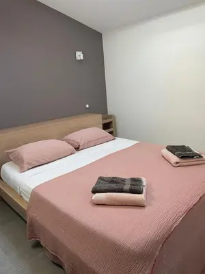 a bedroom with a bed with pink sheets and pink pillows at Gîte Les Alpilles in Eygalières