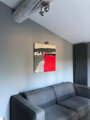 a living room with a couch and a painting on the wall at Gîte Les Alpilles in Eygalières