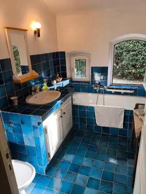 a blue tiled bathroom with a tub and a sink at Maison Robert in La Tour-dʼAigues