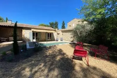a yard with two red chairs in front of a house at Mazet Arlequine in Eygalières