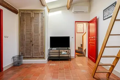 a living room with a television and a staircase at Ecrin au cœur d'Aix-Vue sur la Place de la Mairie in Aix-en-Provence