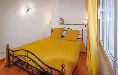 a yellow bed in a room with a window at Sarriette & Romarin in Apt