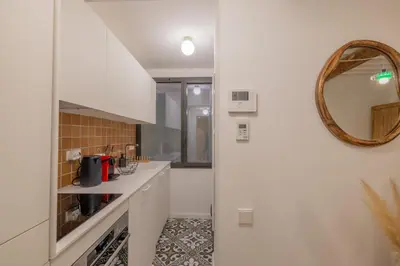 a kitchen with white cabinets and a mirror at Appartement Belle Lettre 2 in Aix-en-Provence
