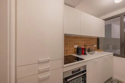 a white kitchen with white cabinets and appliances at Appartement Belle Lettre 2 in Aix-en-Provence