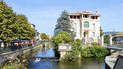 a building next to a river in a city at Le Coeur de L'Isle, Cosy, Hypercentre, Clim, Wifi, TV, Netflix in LʼIsle-sur-la-Sorgue