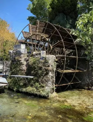 an old waterwheel sitting on the side of a river at Le Coeur de L'Isle, Cosy, Hypercentre, Clim, Wifi, TV, Netflix in LʼIsle-sur-la-Sorgue
