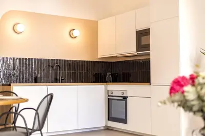 a kitchen with white cabinets and a table and chairs at Charme et Modernité au coeur d'Aix & Cours Mirabeau in Aix-en-Provence