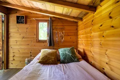 a bedroom with a bed in a log cabin at Cabane Perchée avec Jacuzzi, au Coeur du Luberon in Oppède