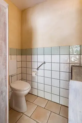 a bathroom with a toilet and a tiled wall at Cabane Perchée avec Jacuzzi, au Coeur du Luberon in Oppède