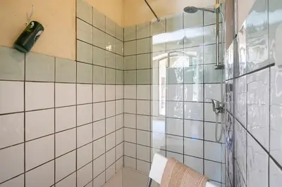 a bathroom with a shower with white tiles at Cabane Perchée avec Jacuzzi, au Coeur du Luberon in Oppède