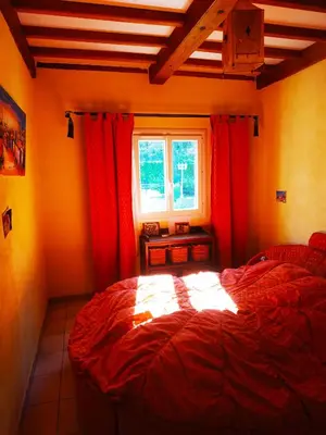 a bedroom with a bed with red curtains and a window at AU BONHEUR et LIBERTÉ in Meyrargues
