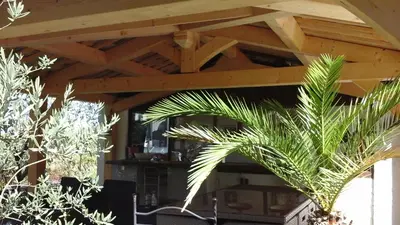 a wooden roof over a patio with two plants at AU BONHEUR et LIBERTÉ in Meyrargues