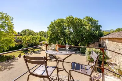 a patio with a table and chairs on a balcony at Gite dans un Mas Provençal avec Jacuzzi in Oppède