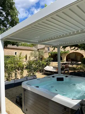 a hot tub under a white pergola at Gite dans un Mas Provençal avec Jacuzzi in Oppède