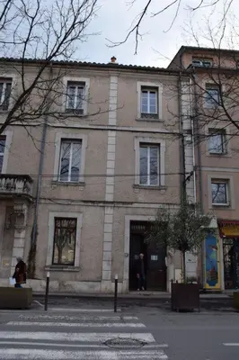 a large brick building on the side of a street at Cozy apartment in LʼIsle-sur-la-Sorgue