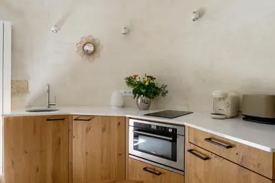 a kitchen with wooden cabinets and a counter top with flowers at Gîte de charme face au Luberon, avec Jacuzzi in Oppède