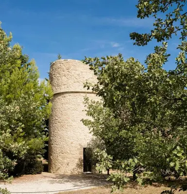 a stone tower with a door in the middle of trees at Gîte de charme face au Luberon, avec Jacuzzi in Oppède