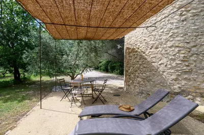 a patio with a table and chairs under a wooden umbrella at Gîte de charme face au Luberon, avec Jacuzzi in Oppède