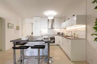 a kitchen with white cabinets and a island with bar stools at Le Jardinet de la Cathédrale in Aix-en-Provence