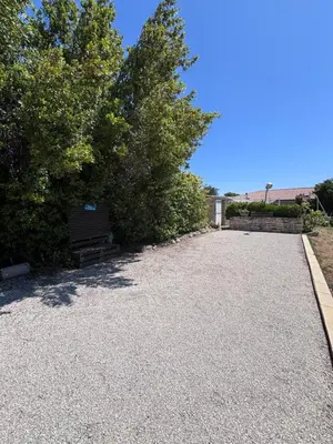 a gravel driveway with a bench and trees at Le pavé in Gordes
