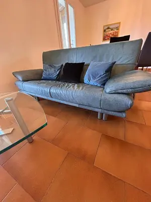 a blue couch in a living room with a glass table at Le Paradis au centre du Vaucluse in Saumane-de-Vaucluse