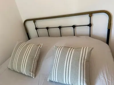 a bed with two striped pillows on top of it at Vacances face au Luberon in Robion en Luberon