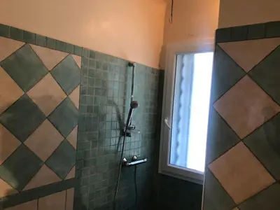 a shower with a glass door and a window at La maison du bon remède in Mazan