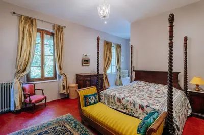 a bedroom with a bed and a chair at Chateau du Jonquier in Mazan