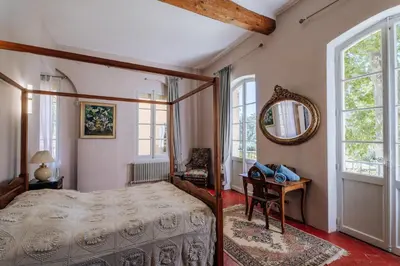 a bedroom with a bed and a mirror and a table at Chateau du Jonquier in Mazan
