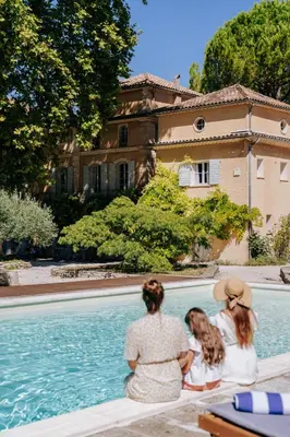 a group of three women sitting next to a swimming pool at Chateau du Jonquier in Mazan