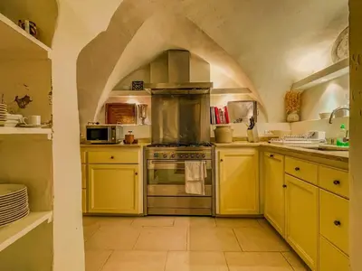 a kitchen with yellow cabinets and a large oven in it at Maison de charme au coeur du village de Gordes in Gordes