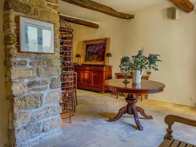 a living room with a table and a brick wall at Maison de charme au coeur du village de Gordes in Gordes