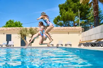 two girls are jumping into a swimming pool at Camping 3 étoiles - Piscine - efaeh0 in Malemort-du-Comtat
