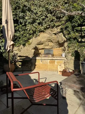 a red chair and an umbrella next to a fire place at CaBaNa 52 La chambre Proche Lourmarin in Cadenet