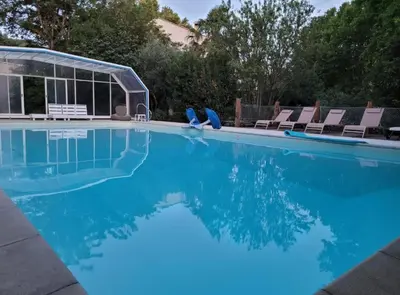 a swimming pool with chairs and blue water at La Maison perchée - Mas de Rousseau in Eyragues